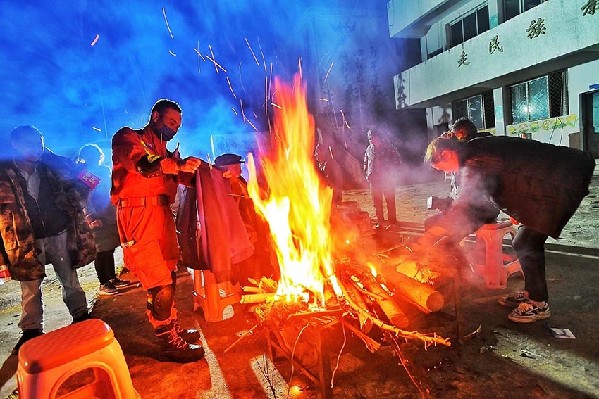 9月5日深夜，消防救援人員在燕子溝鄉(xiāng)排查時(shí)烤干衣服。四川省消防救援總隊(duì)供圖