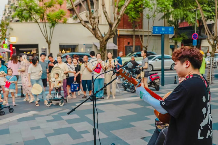 街頭藝人的表演深深吸引路人。玉林街道辦事處供圖