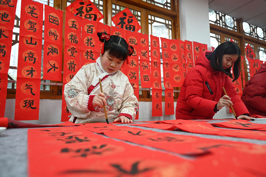 為社區(qū)居民書(shū)寫(xiě)春聯(lián)和“?！弊?。蘭自濤攝