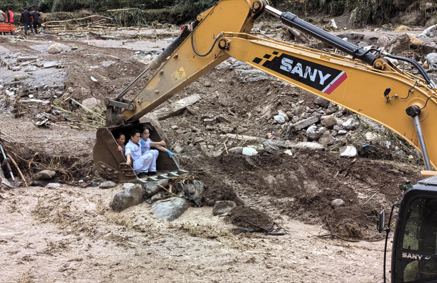 救援人員坐上挖掘機挖斗轉(zhuǎn)運救治受災(zāi)村民。雅安市120急救中心供圖